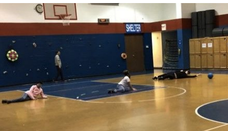 three students with blindfold practicing goalball in the KSSB gym.