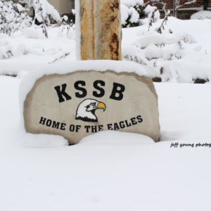 Stone Partially Covered In Snow With Eagle Head And KSSB Home Of The Eagles Carved On The Front.