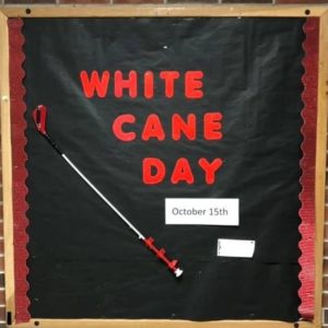 Bulletin Board With Words: White Cane Day And A Small Kiddie Cane Attached.