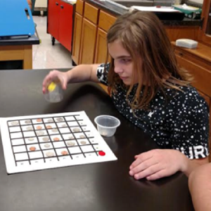 A Student Sitting At A Table With A Bingo Card In Front Of Her.