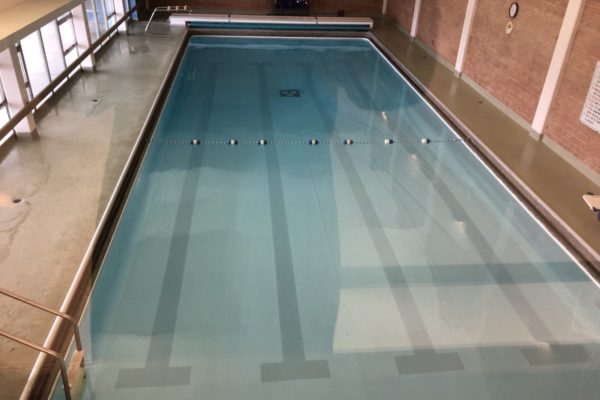 overhead picture swimming pool with a set of benches on the far end and metal steps on the left.