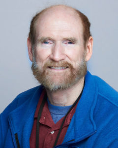 Bob Taylor wearing a maroon shirt and a blue jacket.