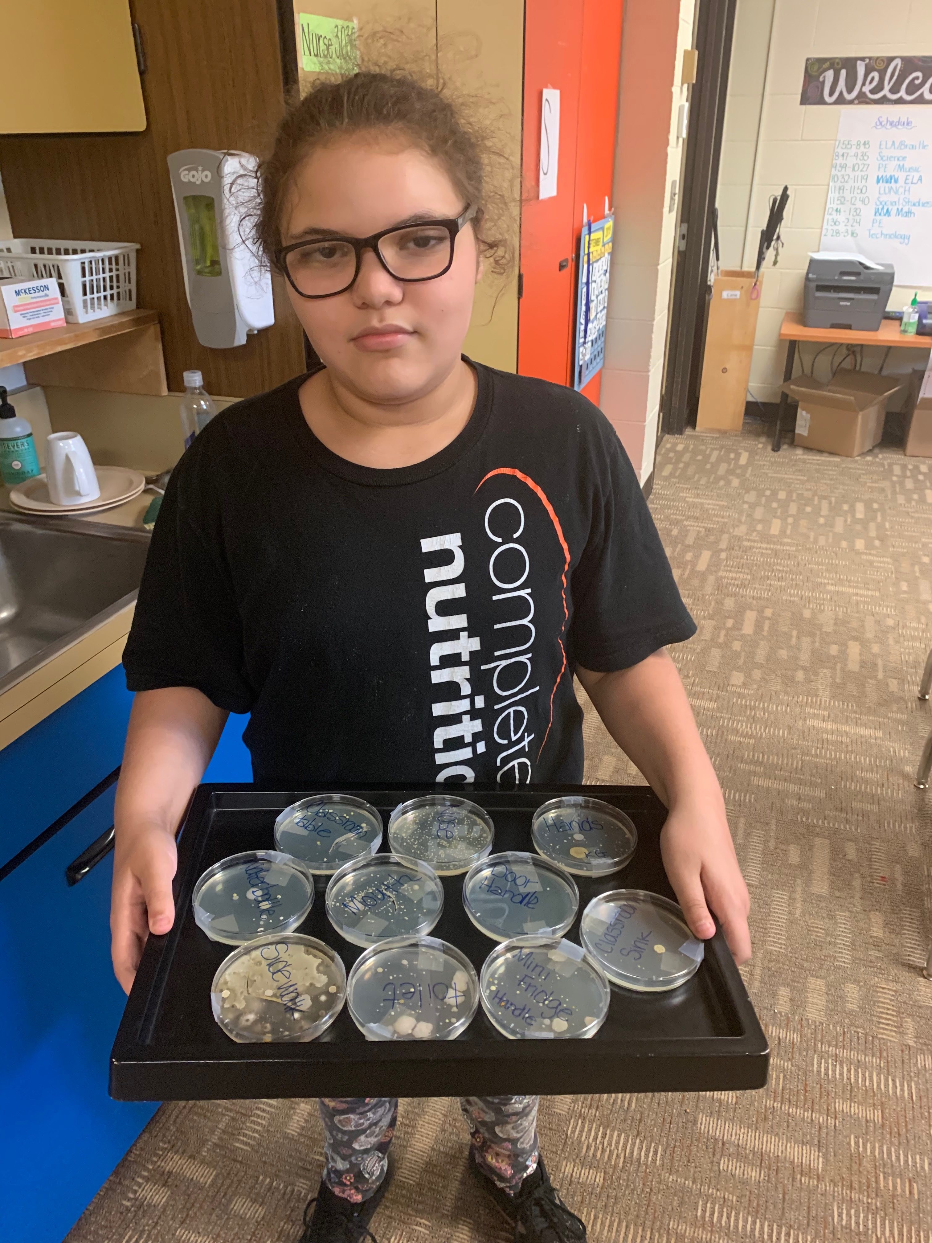 Student holding tray of petri dishes.