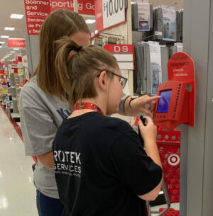 Student and Teacher standing in front of a red wall scanner to view details of the product.