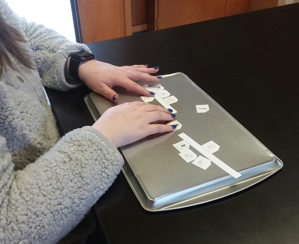 Students with hands on Nemeth Code magnetic squares set on a cookie sheet.