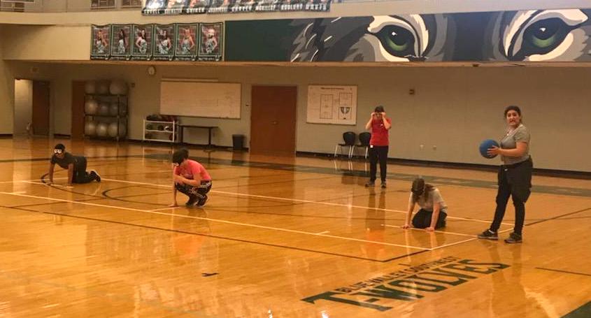 Five students on a gym floor wearing blindfolds and ready to play goalball.