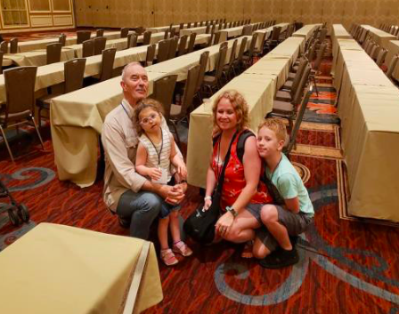 Family sitting near the floor posing for a picture in a large conference room space.