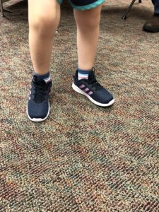 child wearing navy blue tennis shoes with three pink stripes on the side