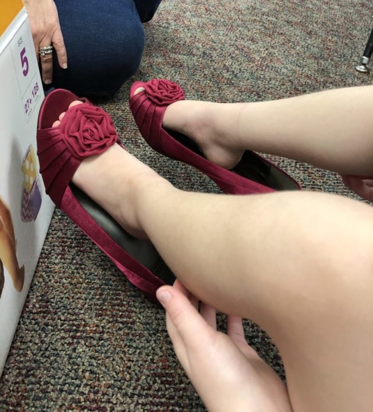 child putting on red, open toed high heels