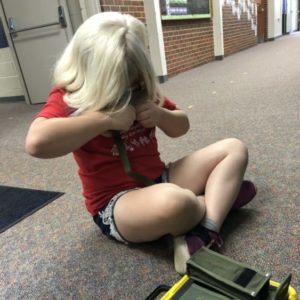 Girl With Blonde Hair And Red Shirt Sitting On The Floor Looking At Different Monculars