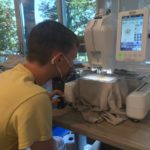 student sitting at embroidery machine watching for when the thread needs to be changed