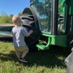 little boy exploring a big wheel of a tractor