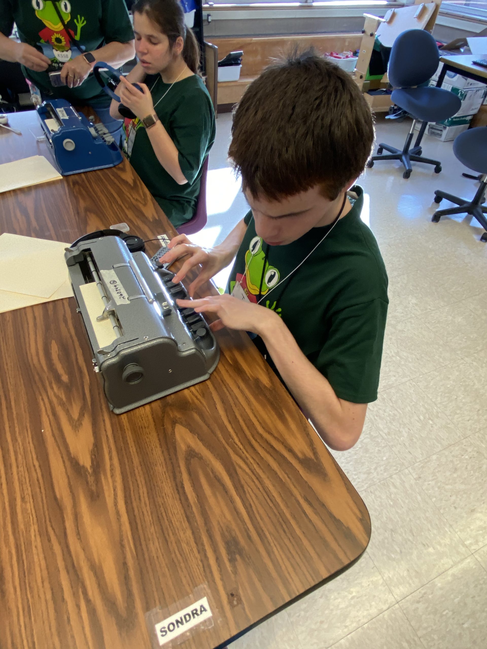 two students sitting a table working on their braillewriter
