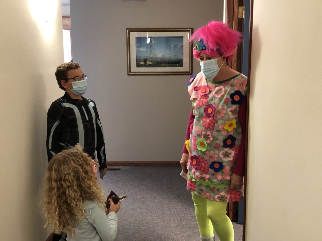 adult dressed as Poppy from Trolls talking to two participants of a low vision collaboration clinic