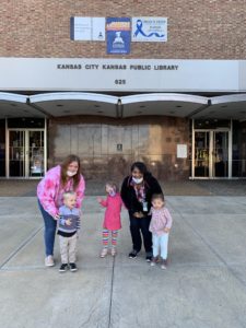 2 teachers and 3 students stand outside of a library to pose for a picture