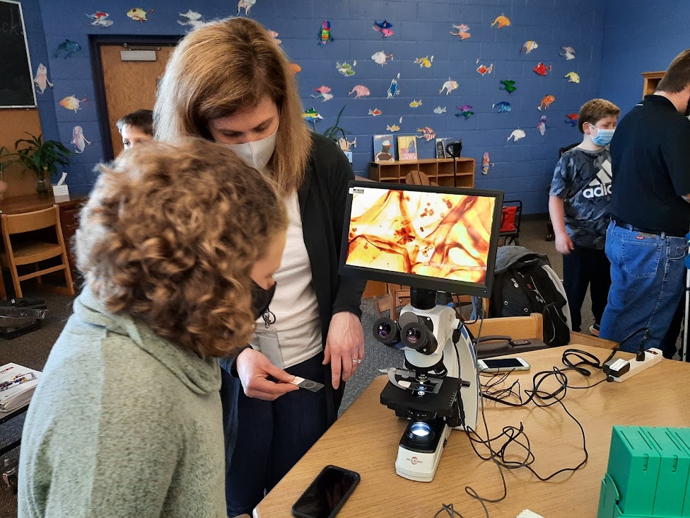 Student looking at fibers under a microscope with Molly Reardon