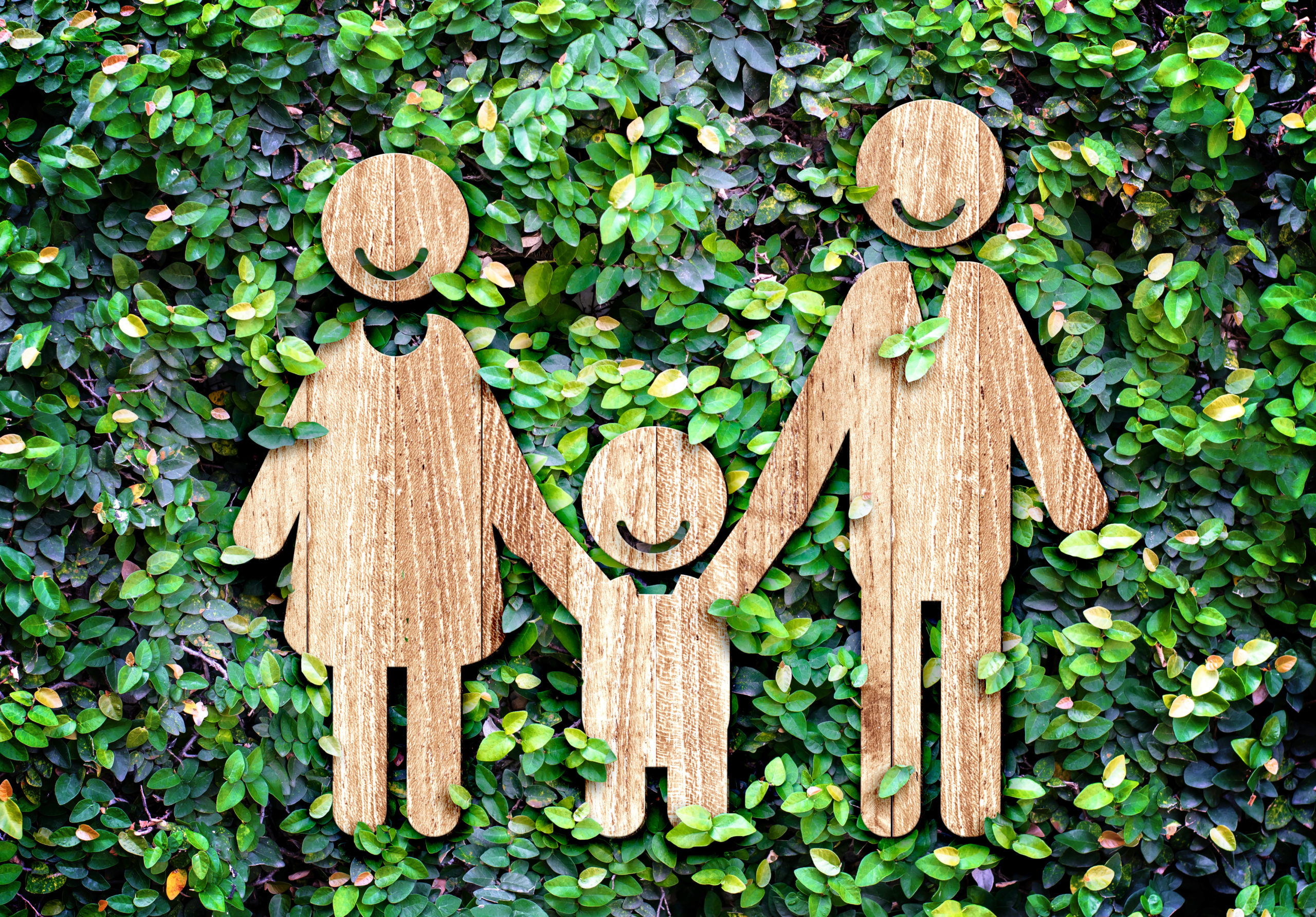 a wood cutout of a family against a leafy background