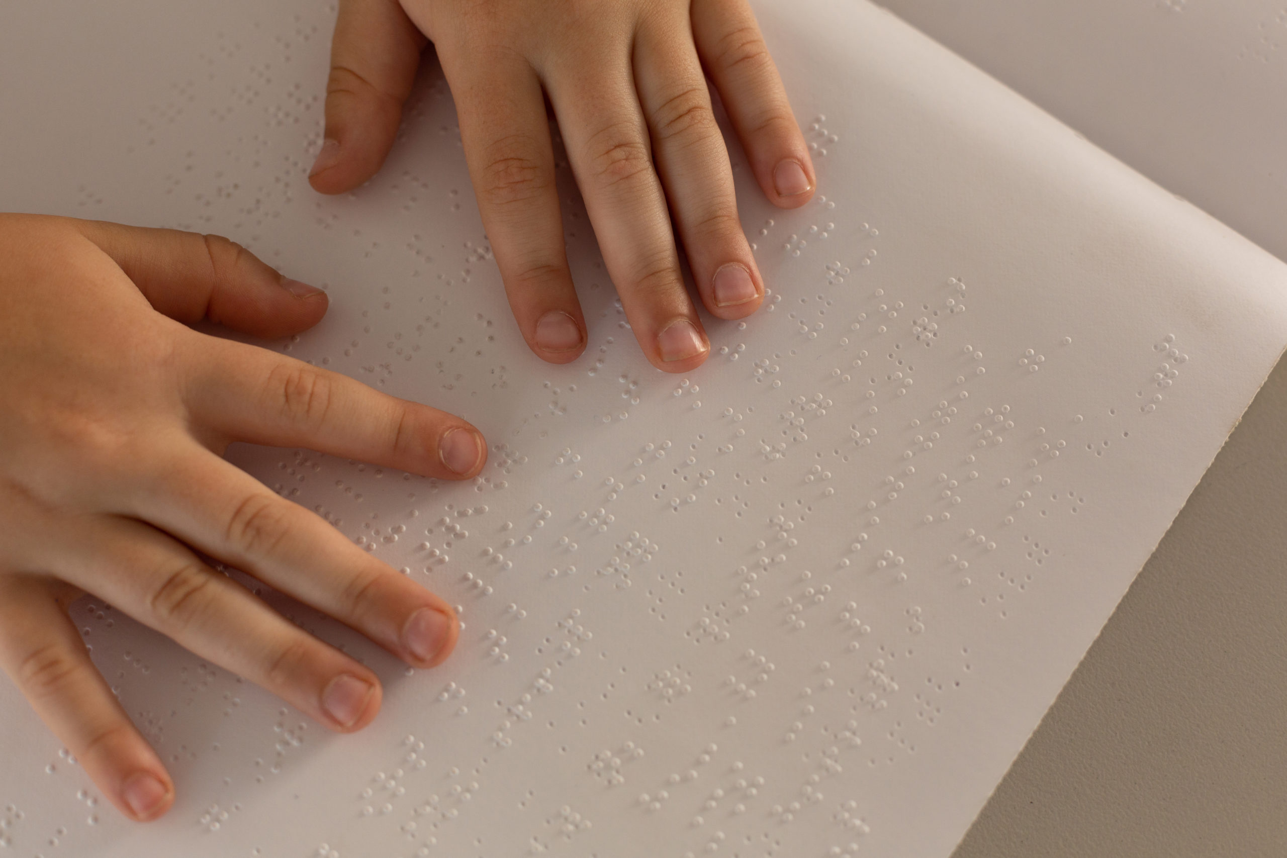 hands reading braille in a book