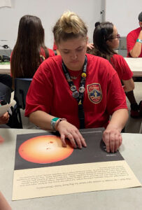 Zoe learns about astronomy by using tactile graphics of planets and stars