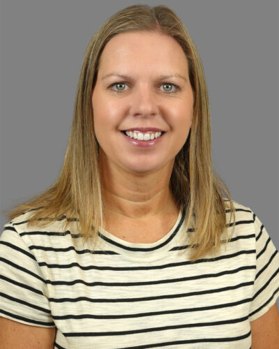 Amber Hanson has long blonde hair, wears a black and white striped shirt and smiles for the camera.